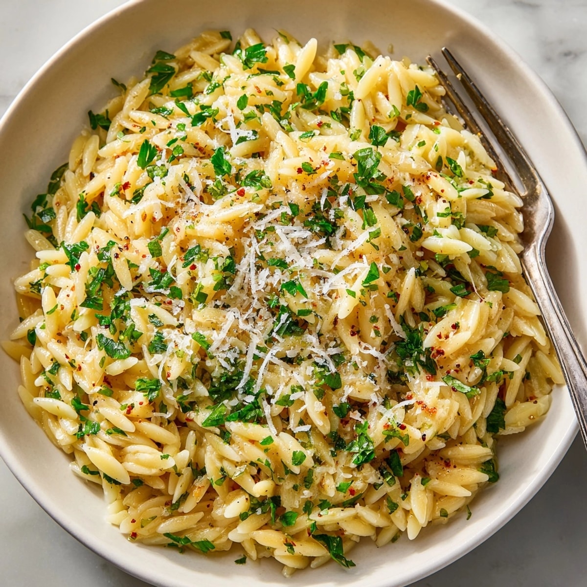 Orzo with Lemon, Herbs, and Parmesan served warm in a skillet, garnished with fresh herbs.