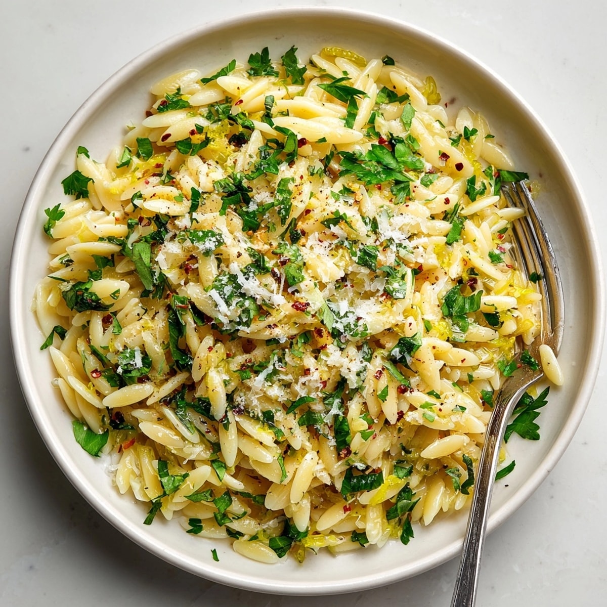 Close-up of orzo with lemon, herbs, and parmesan, perfect for a light Mediterranean side dish.