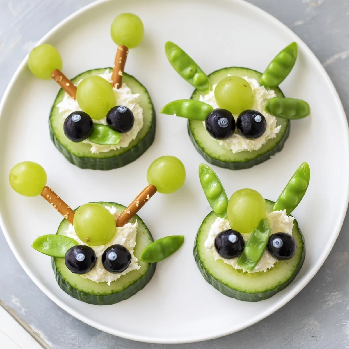 Vibrant platter of Little Green Men Alien Snack Attack snacks: creamy cucumber faces with olives and silly candy eyes.