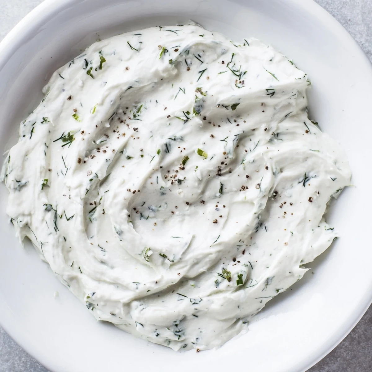 Creamy Greek Yogurt Herb Dip, speckled with fresh herbs, is ready to be scooped with crisp veggies.