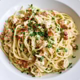 Close-up of Chicken Carbonara featuring al dente spaghetti coated in rich egg-Parmesan sauce with diced bacon and savory chicken.