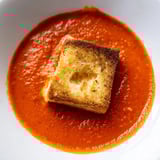 Fresh roasted tomato soup served with bite-sized grilled cheese croutons for a cozy meal.