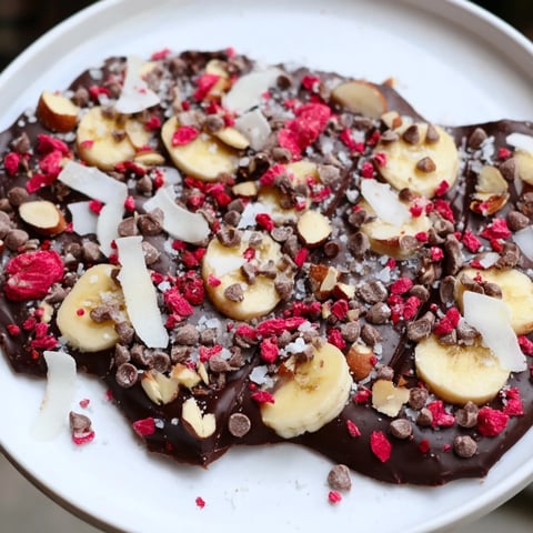 Delicious Chocolate Banana Bark, frozen and broken, adorned with almonds, coconut, and berries.