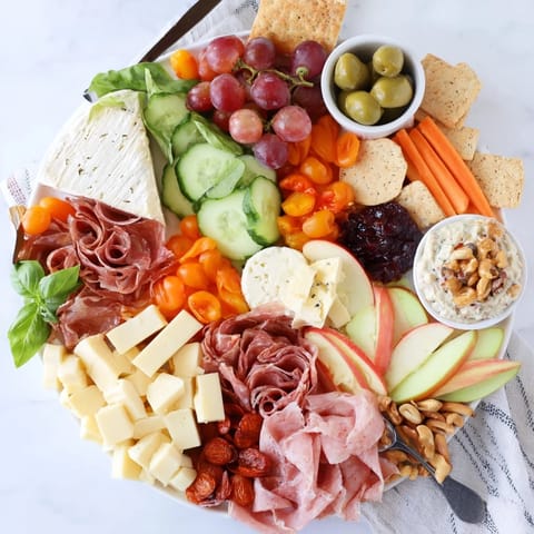 Vibrant Girl Dinner Platter filled with snacks, cheeses, and fresh veggies to enjoy.  
