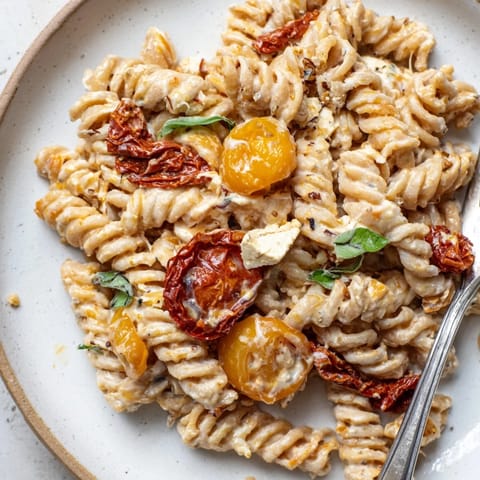 Creamy Baked Feta Pasta 2.0 topped with caramelized onions and fresh basil leaves.  