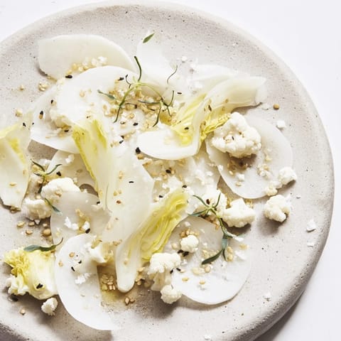 Enjoy a refreshing "Tundra Trek" salad: see the delicate arrangement of pale vegetables and garnishes.