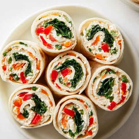 These creamy Christmas Scarf Tortilla Roll-Ups feature roasted red peppers and spinach, perfect for a vegetarian snack.