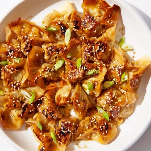 Golden-brown air fryer frozen dumplings glistening with a savory sesame oil glaze and sesame seeds.