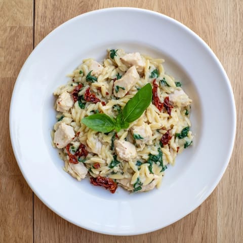 Tuscan Chicken Orzo served steaming hot in a pan, featuring tender chicken, garlic, and melted Parmesan for a hearty meal.  
