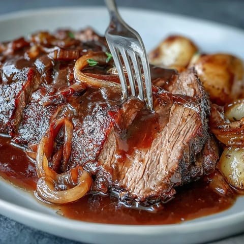 A tender pot roast slow-cooked with onion soup mix, surrounded by carrots and potatoes, creating a rich and comforting family meal.