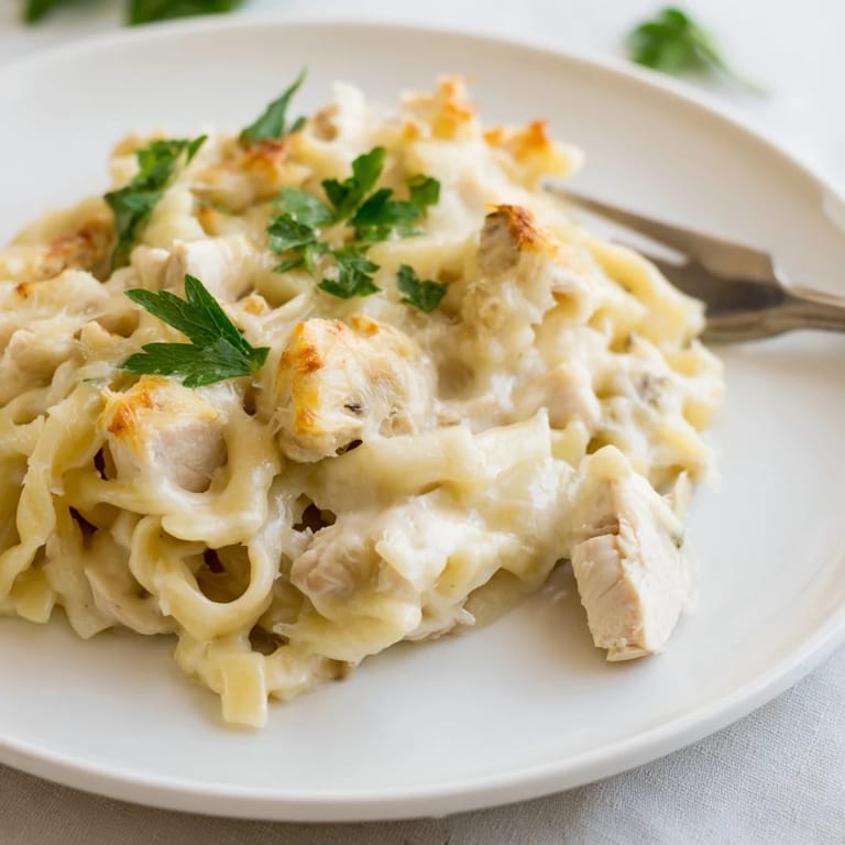 A delicious close-up of creamy Chicken Fettuccine Alfredo Bake, topped with melted mozzarella and Parmesan.