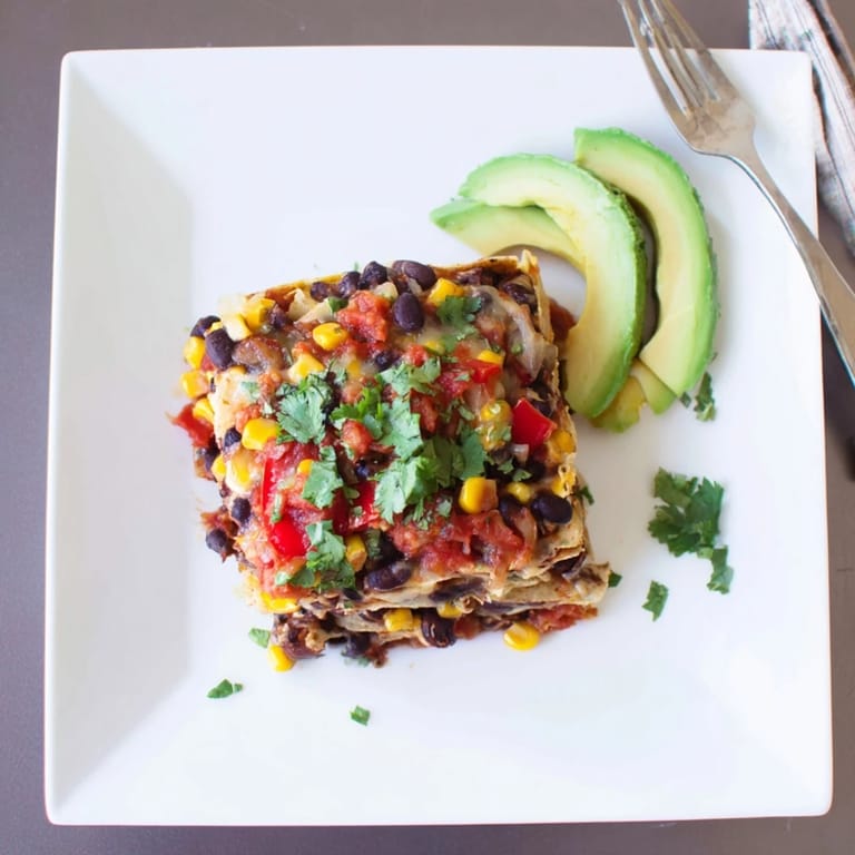A flavorful layered Quick Black Bean and Corn Tortilla Casserole showcasing golden, bubbly cheese and vibrant ingredients.