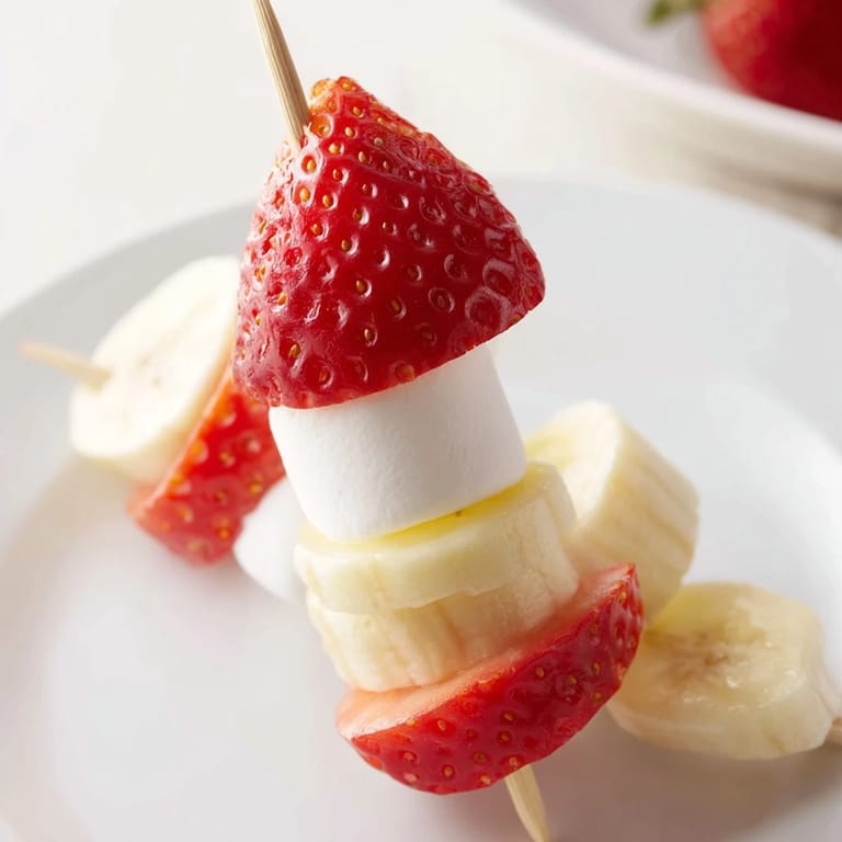 Vibrant Strawberry Banana Santa Sticks, a cheerful treat with fresh fruit and marshmallow tops, perfect for holiday snacking.