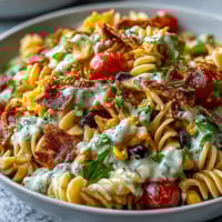Colorful Taco Pasta Salad with Doritos and Avocado Ranch dressing, topped with fresh vegetables and shredded cheese.  